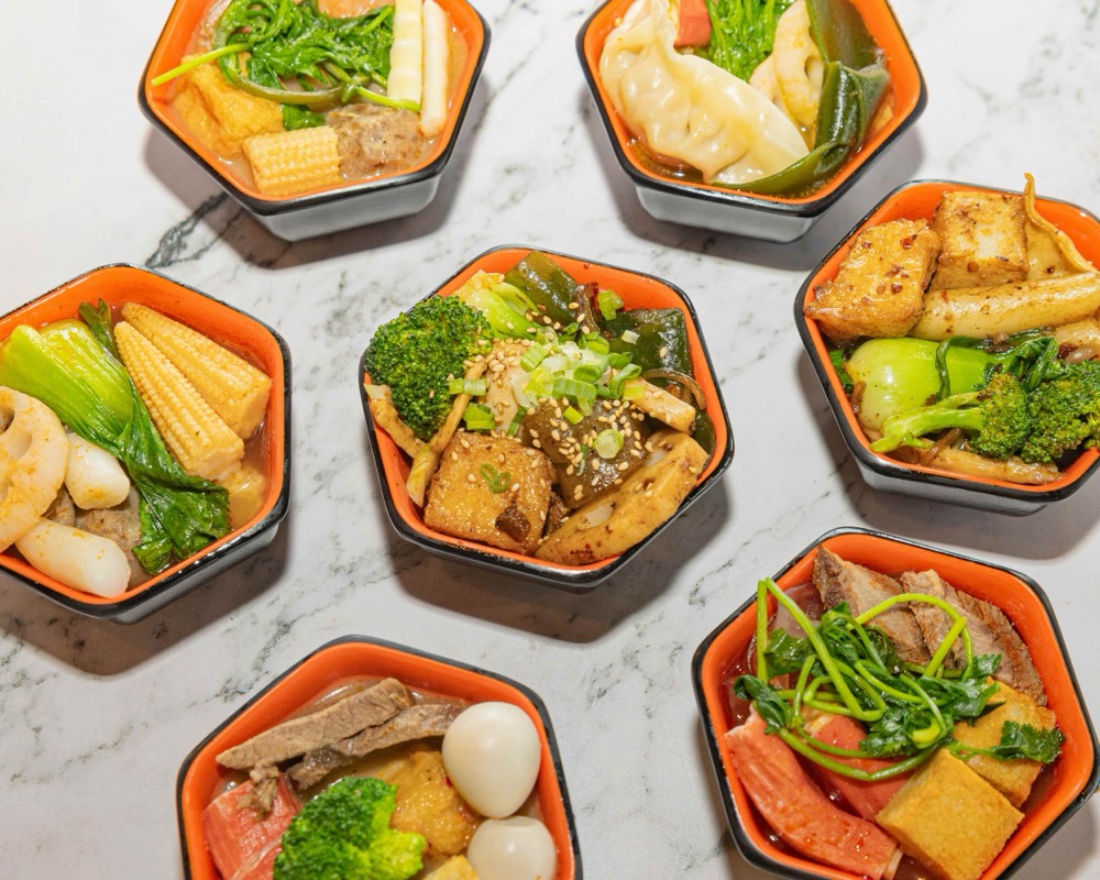 Top-down spread of Fire Wok Hot Pot signature broth bowls with fresh meats, seafood and vegetables