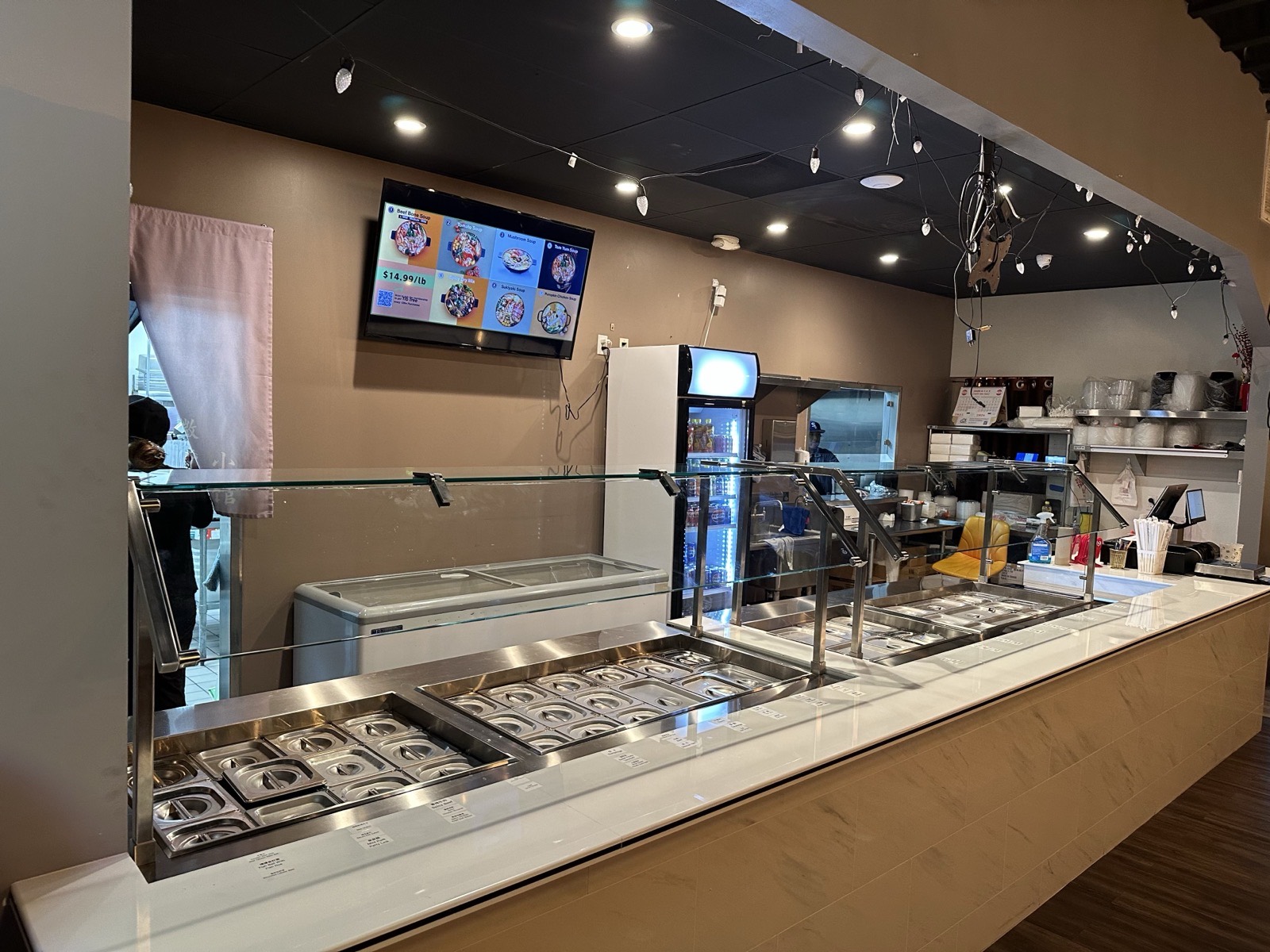 Fire Wok Hot Pot fresh ingredient bar β a self-serve station of fresh meats, seafood, vegetables, tofu and noodles behind a glass guard